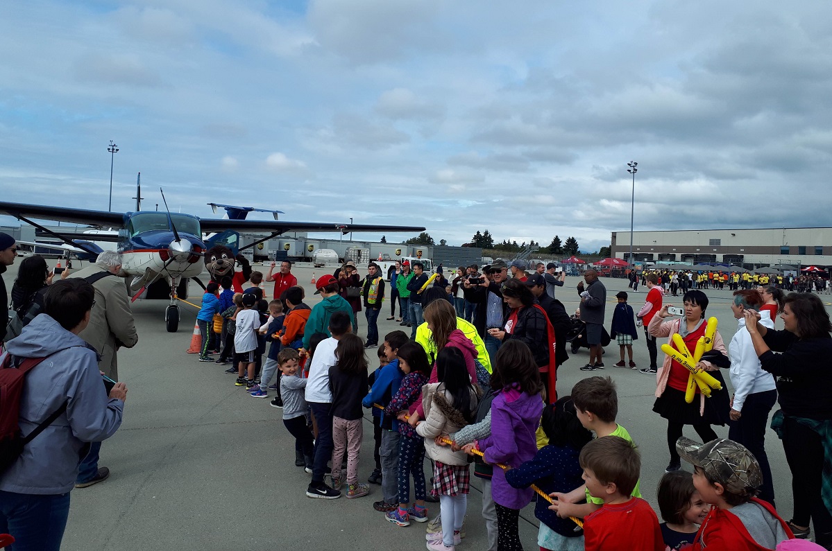 Children hold a long rope tied to a small plane.