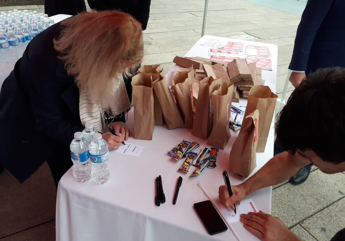 Two people pack a bagged snack and write notes to local children.