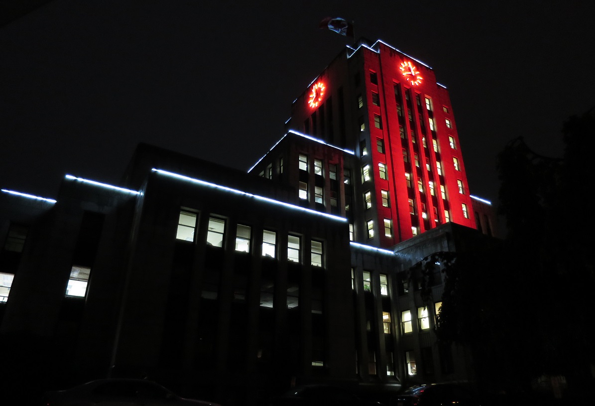 A large civic building glows red at night.