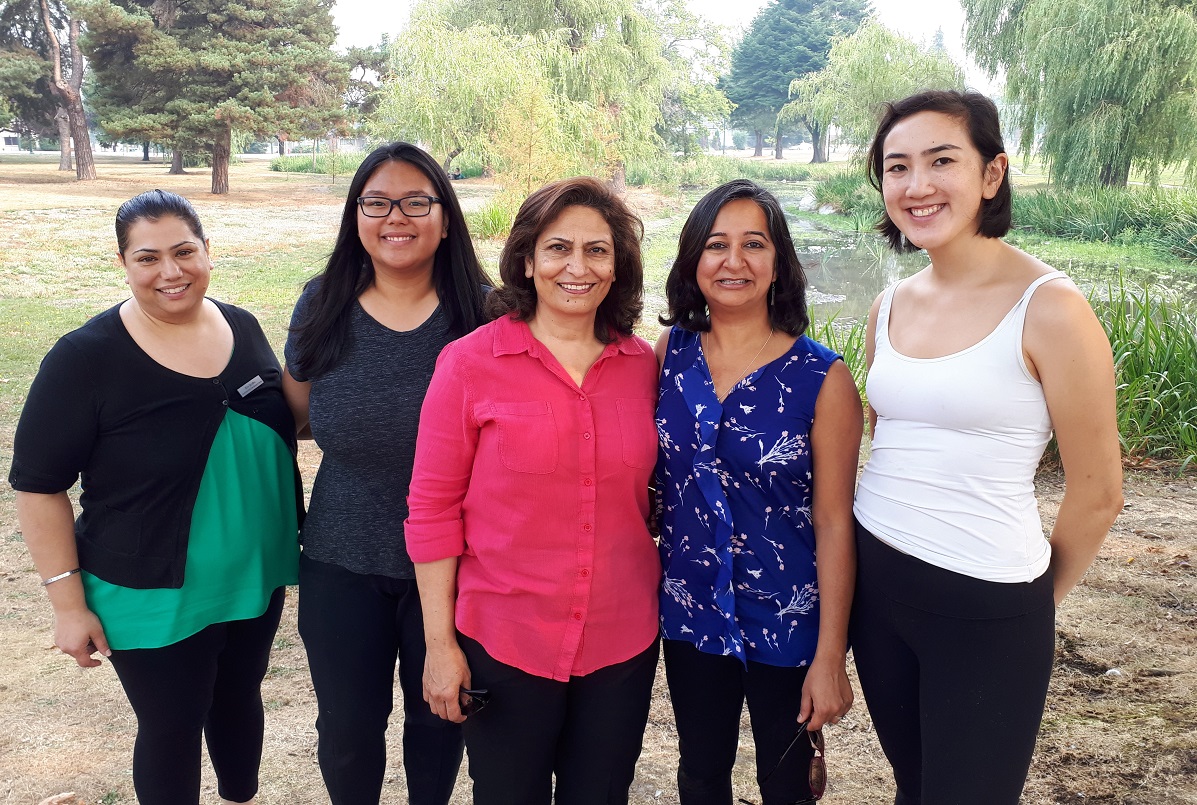 Five women stand next to each other a smile at the camera.