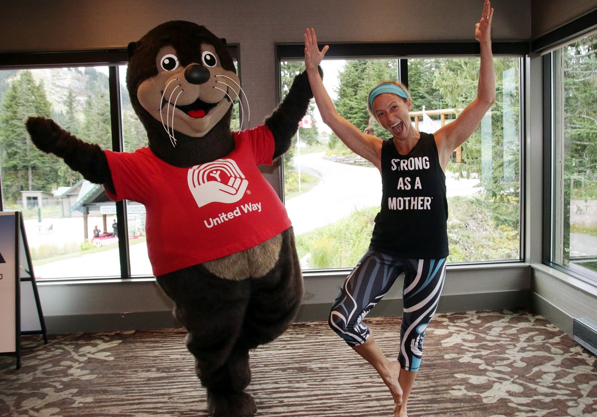 A sea otter mascot does yoga with a teacher.