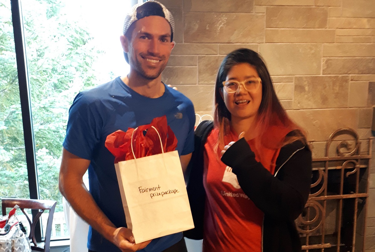 A man and a woman smile at the camera. He holds a prize.