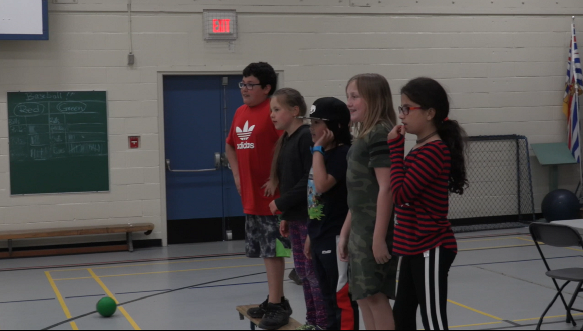 A group of kids line up in a gym ready to play.
