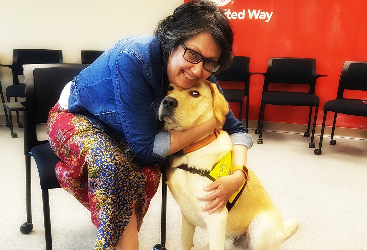 A woman hugs her dog and they both look at the camera.