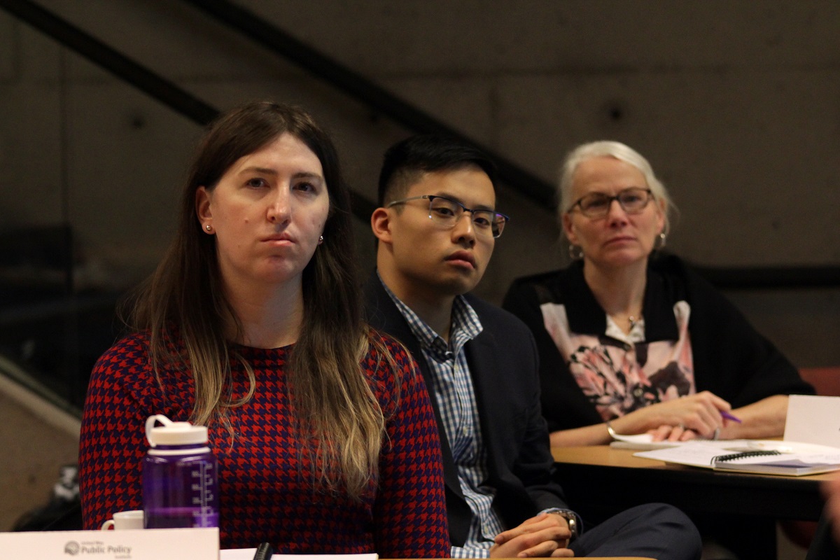 Two women and a man listen to a lecture.