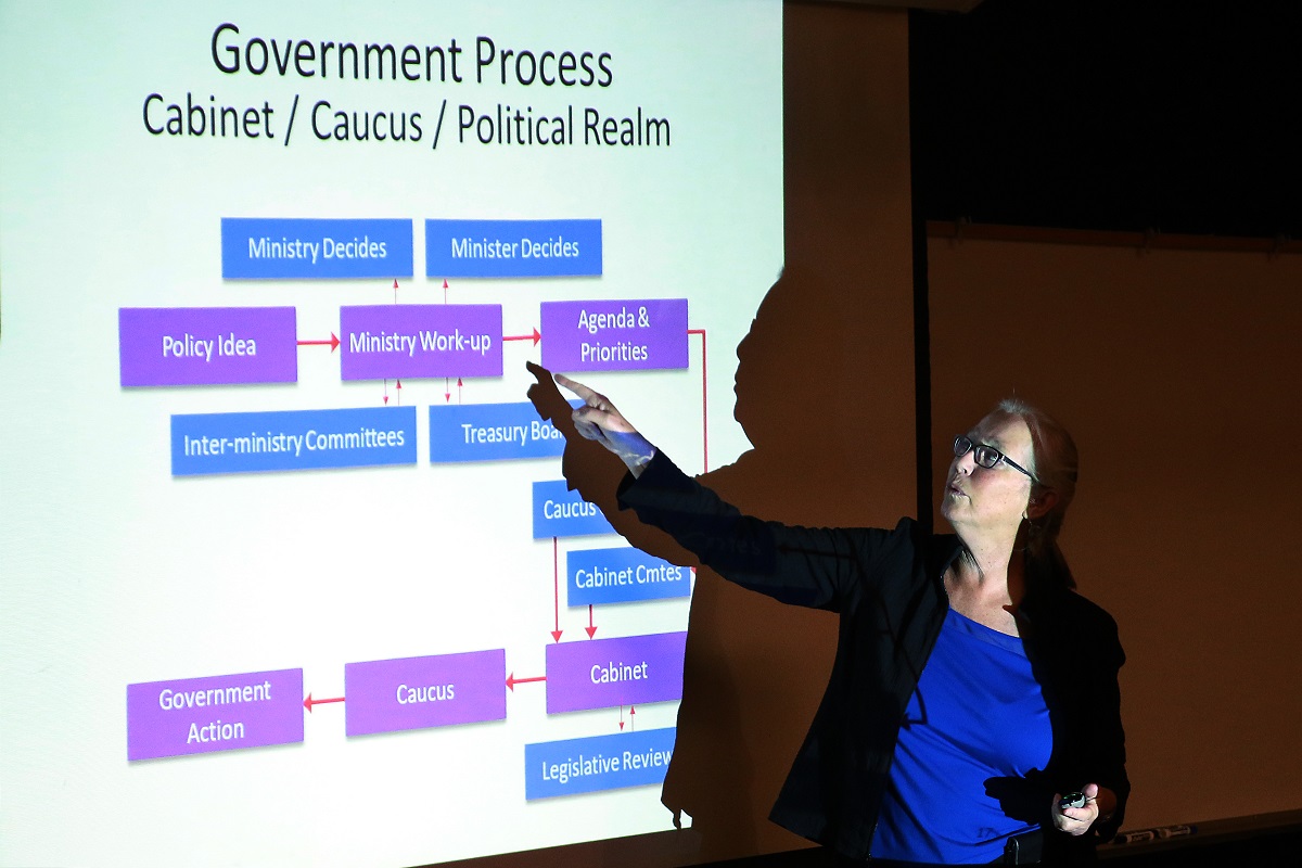 A woman stands in front of a screen.