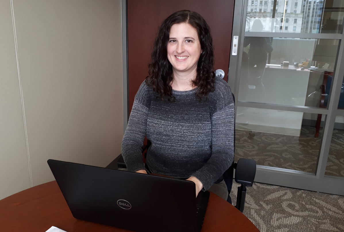 A woman smiles behind her computer.