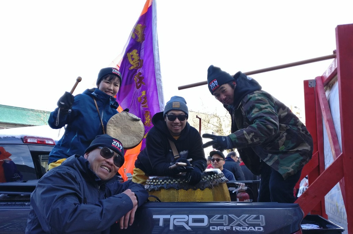 A group of people smile with their drums in the back of a truck.