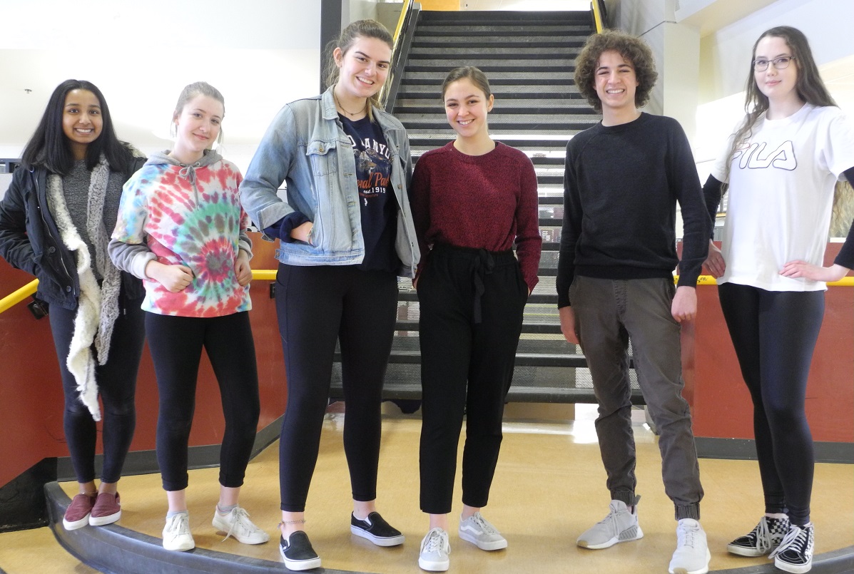 A group of teenagers pose on a staircase.